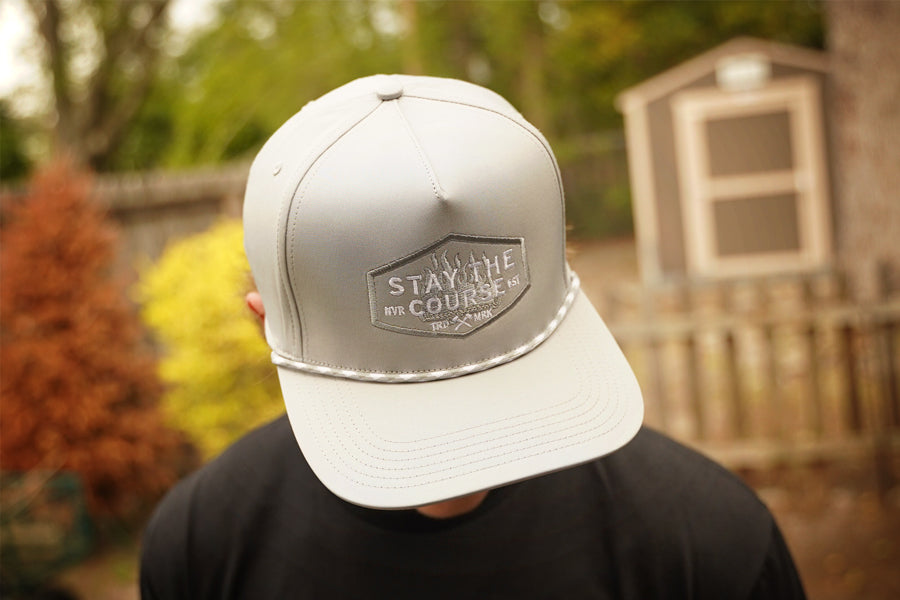 Person wearing a gray cap with a logo and text, outdoors.