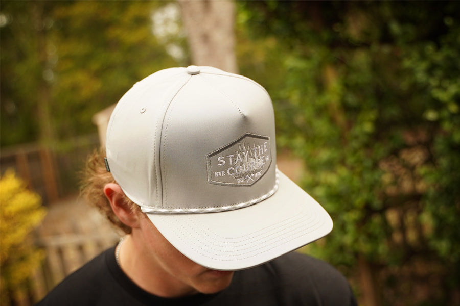 Person wearing a gray cap with a logo outdoors