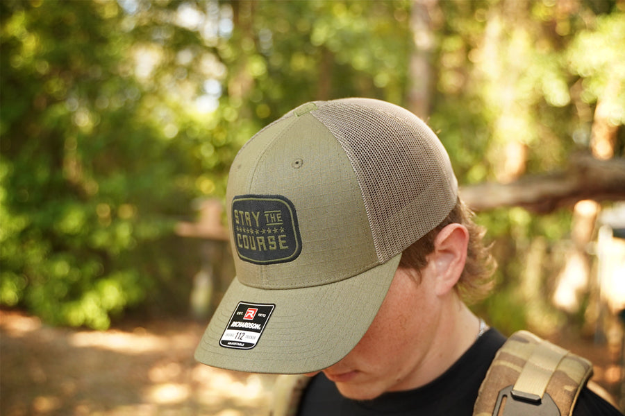 Person wearing a green cap with a logo and text in a forest setting