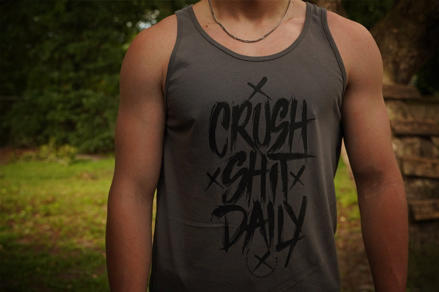 Person wearing a tank top with 'CRUSH SHIT DAILY' text outdoors.