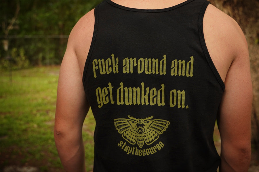 Person wearing a black tank top with green text and logo in an outdoor setting