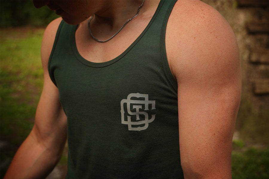 Person wearing a green tank top with a logo outdoors