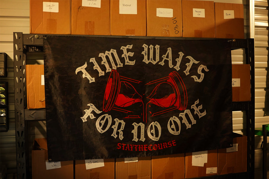 5x3 black camo flag with white and red design that says ice waits for no one, hanging in a warehouse.