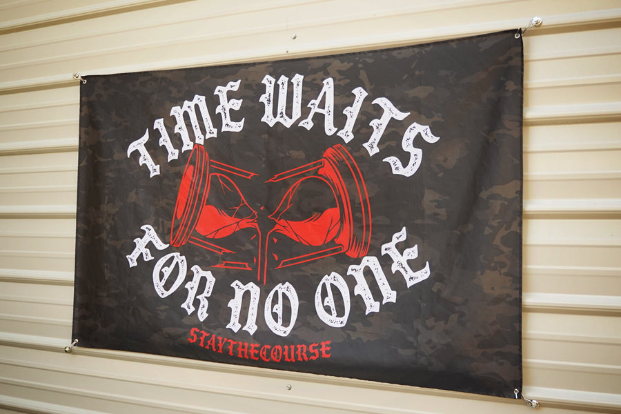 5x3 black camo flag with white and red design that says ice waits for no one, hanging on a metal siding building