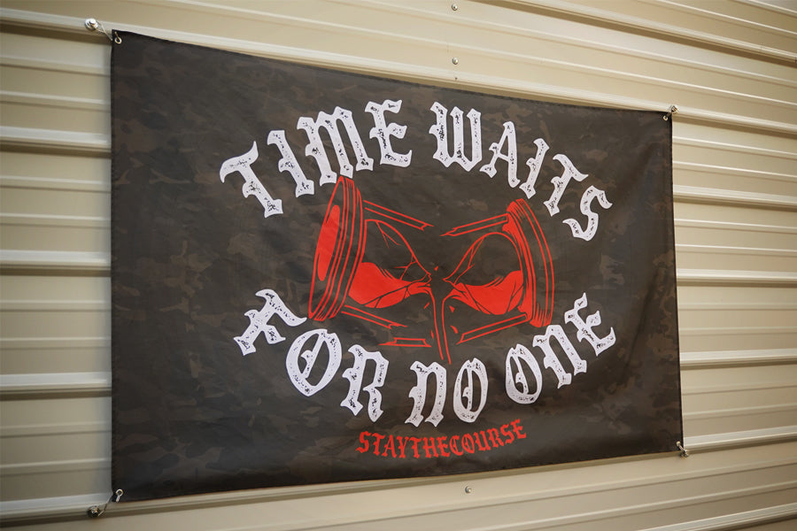 5x3 black camo flag with white and red design that says ice waits for no one, hanging on a metal siding building